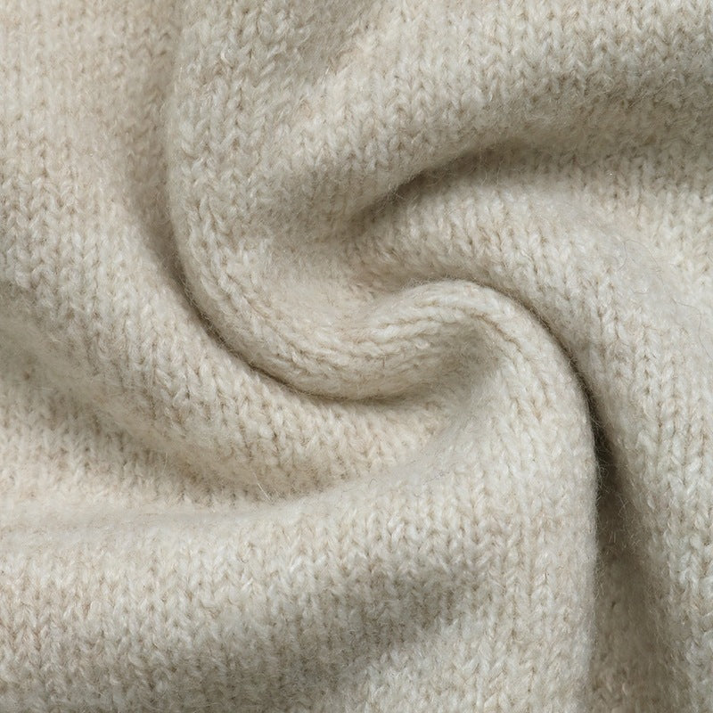 A close-up of soft knit fabric in a warm off-white or cream tone, arranged in a gentle spiral to show texture and drape.