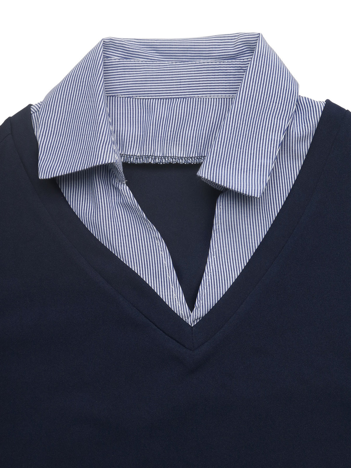 A close-up of a navy blue V-neck knit sweater layered over a light blue and white striped button-down shirt collar.