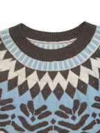 Close-up of a knit sweater showing a crew neck with a dark brown ribbed collar, a light blue and cream geometric yoke pattern, and a matching light blue and dark brown knit body.