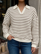 A woman wearing a cream and dark brown horizontally striped knit polo sweater with a waffle texture, paired with blue jeans.