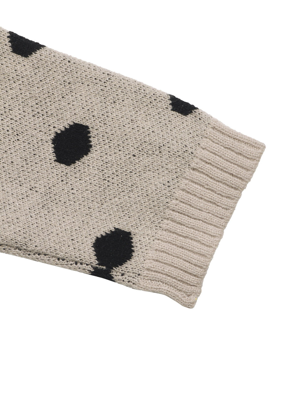 Close-up of a knit sleeve in a light beige or oatmeal color with black polka dots and a ribbed cuff, shown on a plain white background.