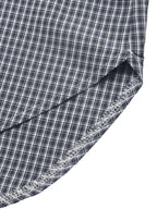 Close-up of a folded plaid fabric with a dark navy and white checkered pattern, showing the texture and raw stitched edge against a white background.