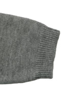 Close-up of a gray knit sleeve with a ribbed cuff on a plain white background.