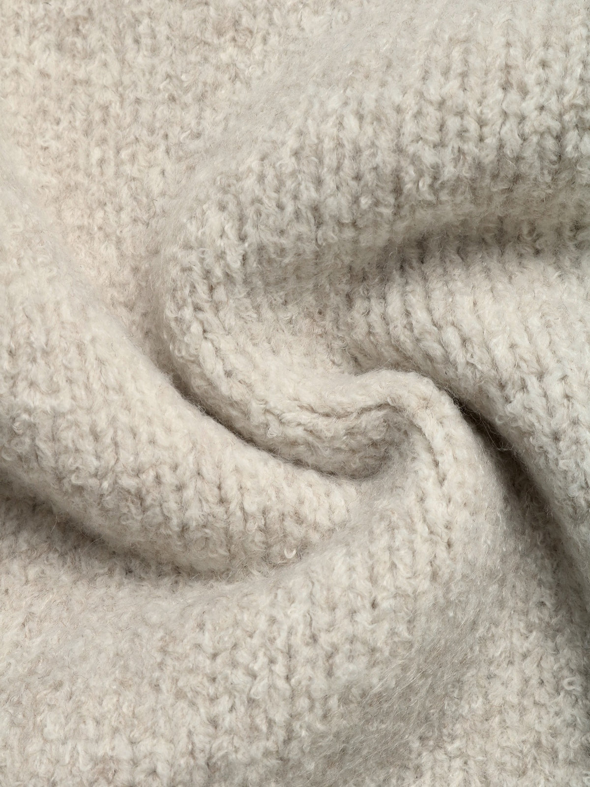 A close-up of a soft, textured knit fabric in a warm off-white or cream color, shown with a gentle swirl to highlight the yarn texture and stitch detail.