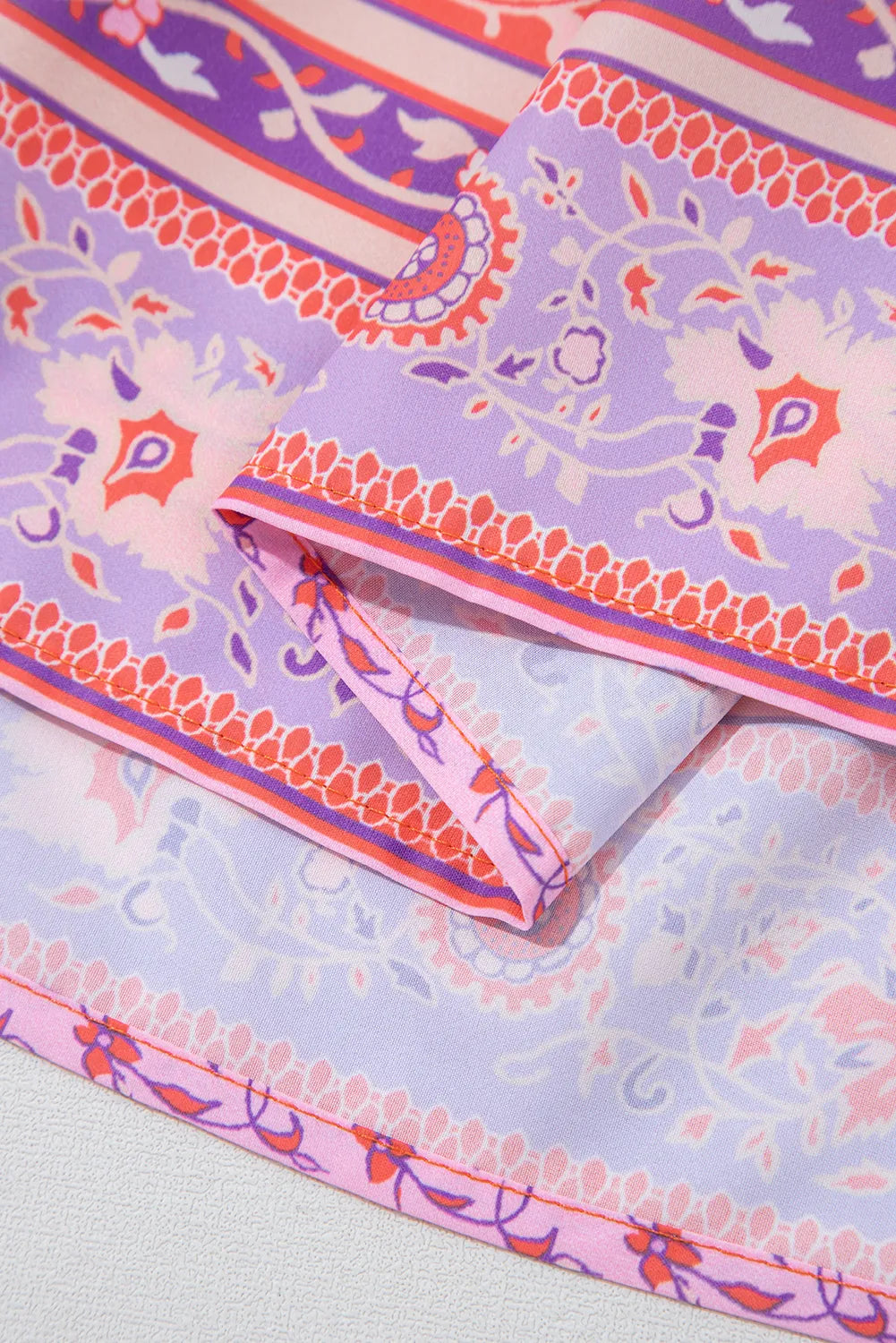 Decorative fabric with purple and pink patterns on a light gray background