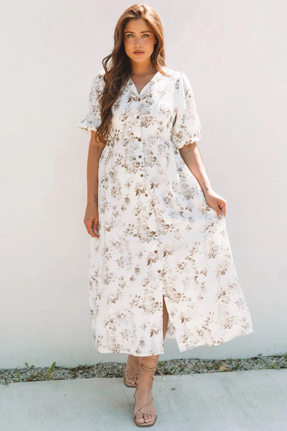 Woman wearing a white floral dress against a plain background