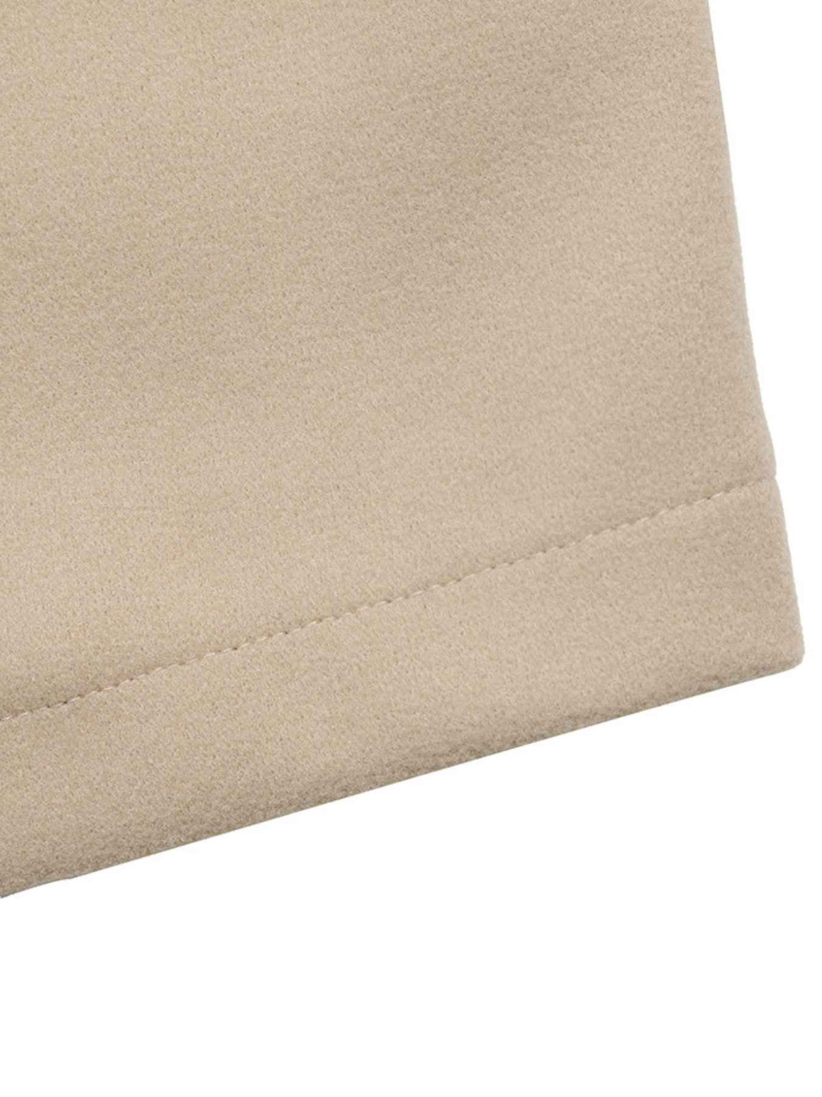 Close-up of a beige fabric surface with a stitched hem or folded edge against a white background.