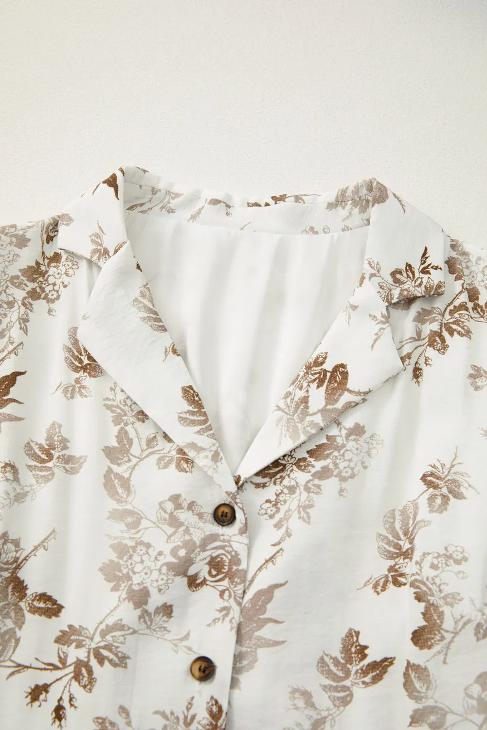 Floral patterned shirt with brown accents on a white background