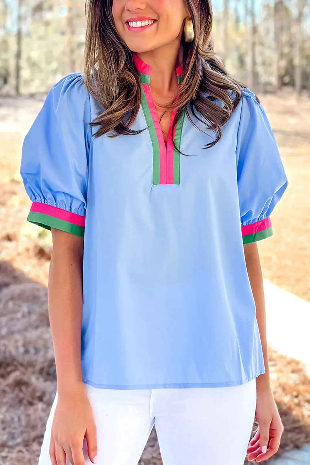 Woman wearing a light blue blouse with colorful trim in an outdoor setting